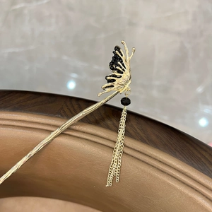 Detailed view of a golden butterfly hair pin with black beads and long chain tassels