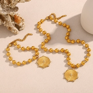 Set collana e bracciale a sfere placcato oro 18K con ciondolo a stella su fondo beige