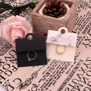 Close-up of gold and silver rings displayed on marble patterned jewelry paper cards