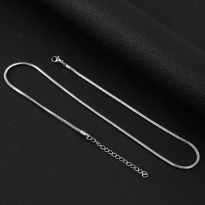 Gros plan d'un collier chaîne serpent argenté avec fermoir mousqueton et chaînette d'extension