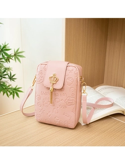 Detailed view of pink PU leather crossbody bag featuring embossed text and gold crown tassel