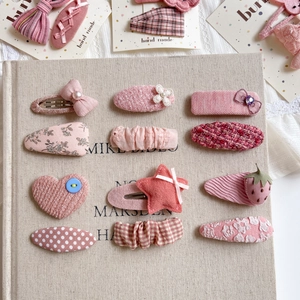 12-piece set of pink fabric hair clips with floral, heart, and star patterns for girls