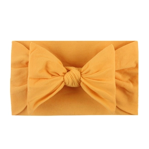 Detail of soft bright yellow nylon headband with a large elastic bow for infants