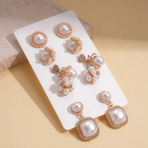 Five-pair gold alloy earring set with faux pearls and rhinestones on display