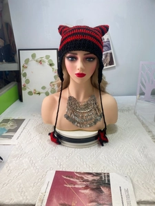 Detail of red and black striped handmade crochet knit hat with cat ears and tassels