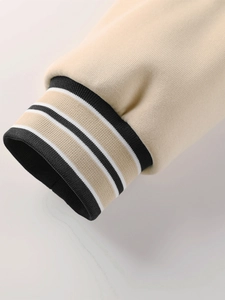 Détail des poignets en maille côtelée à rayures noires et blanches sur une veste beige