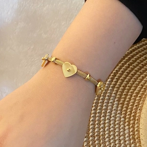 Détail d'un élégant bracelet en or avec des pendentifs en forme de cœur portés au poignet