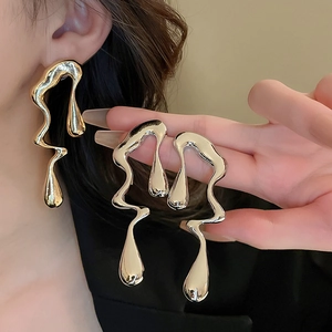 Close-up of irregular liquid metal lava earrings in gold and silver finish