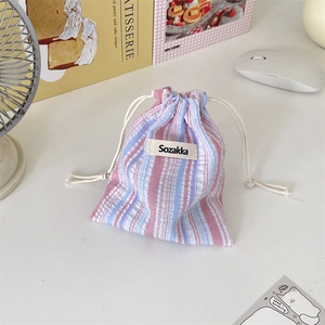 Nahaufnahme der rosa-blau gestreiften Kordelzugtasche mit Sozakka-Etikett auf dem Tisch