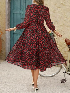 Vue de dos d'une robe longue fleurie noire à grand ourlet dans un décor de vacances