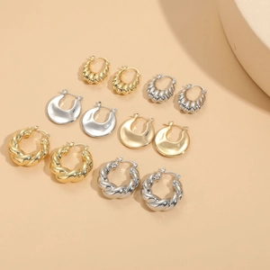 Detail shot of five pairs of 14K gold and silver geometric earrings on a beige background
