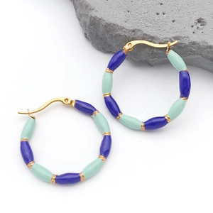 Detail of gold bamboo-style earrings with blue and mint green enamel beads on a grey rock