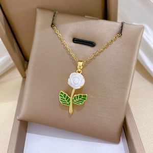 Detail of elegant gold-tone flower necklace with white rose and green leaves in a gift box