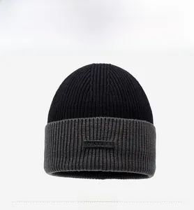 Detail view of the thick ribbed knit texture and black leather label on the beanie