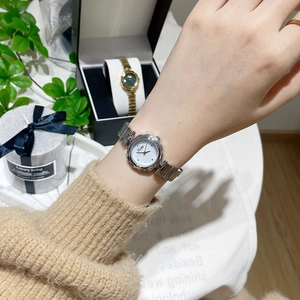 Detail of silver flower-shaped case watch worn on wrist with floral link band
