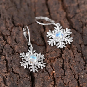 Boucles d'oreilles flocon d'argent avec pierre de lune synthétique sur du bois