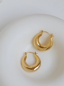 Macro detail of chunky gold hoop earrings with polished finish and latch back closure