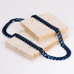 Deep blue stainless steel Cuban link chain necklace displayed on beige textured stones