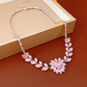 Detailed view of silver necklace with pink heart and marquise stones on jewelry box