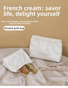 Detail of creamy PU leather makeup bag with pleated edges and gold metal clasp closure