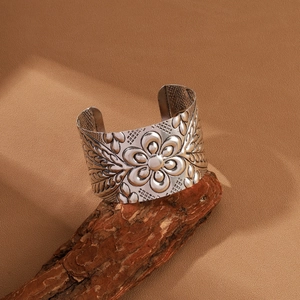 Vintage embossed silver wide open bangle with floral patterns on natural wood stand