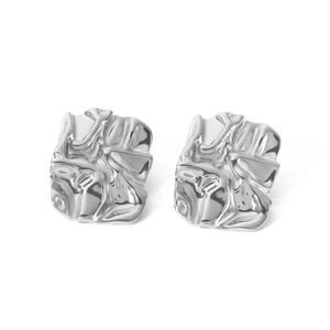 Macro detail of silver square earrings with irregular hammered metallic texture