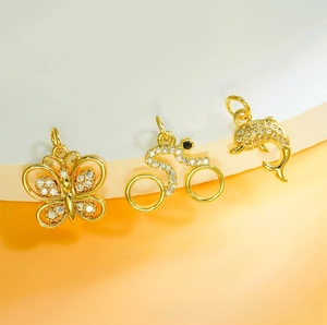 Detail of gold-plated micro-pave zircon charms featuring butterfly, dolphin and bike shapes