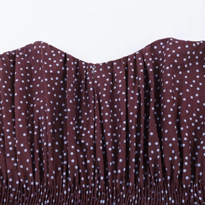Close-up of brown-red fabric with blue polka dots and elastic pleated texture