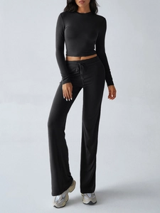 Detail showing high-waisted drawstring yoga flare pants and long sleeve crop top in black