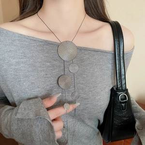 Detail shot of five metallic circles with spiral textures on a minimalist sweater chain