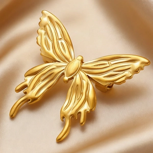 Close-up of golden butterfly brooch with textured wings on luxury silk background