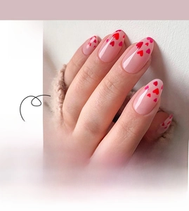 Detail of almond-shaped press-on nails with red heart patterns for Valentine's Day