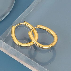 Detailed close-up of oval gold earrings with S925 silver hallmarks on acrylic stand