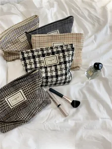 Detailed overhead view of assorted tweed plaid makeup bags with logo patch and zipper