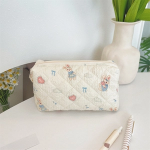 Dettaglio della borsa trucco trapuntata color crema con graziosi motivi a coniglio