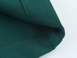 Detail shot of dark green straight trousers showing durable canvas fabric and double stitching