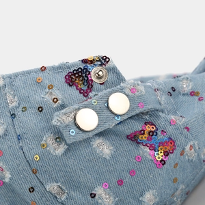 Close-up of distressed denim hat with colorful sequins and silver metal buttons