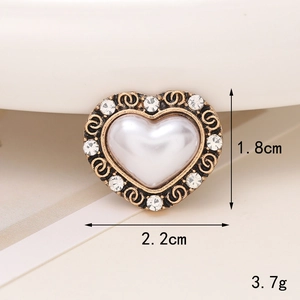 Macro detail of a vintage heart charm with pearls and rhinestones showing 2.2cm size