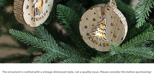 Close-up of wooden XMAS ornament with laser-cut reindeer and trees on green pine branches