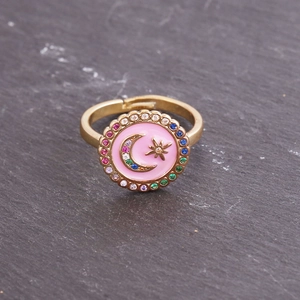 Macro shot of gold ring with pink enamel disc and colorful zircon star moon pattern