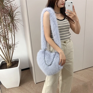 Lavender plush heart-shaped crossbody bag with silver chain detail on a model