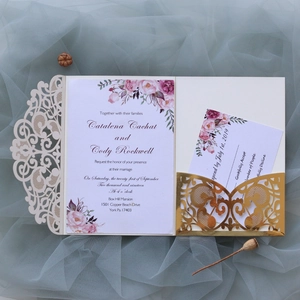 Flat lay of laser-cut wedding invitation set with floral card and gold belly band