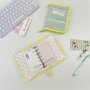 Detailed view of quilted fabric binder with 6-ring metal clips and blue checkered pattern