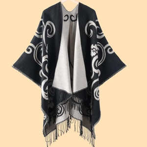 Detail of a double-sided black and white cashmere-like shawl featuring paisley patterns and tassels
