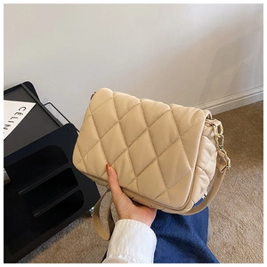 Detail of beige quilted cotton handbag featuring a golden metal chain strap and soft texture