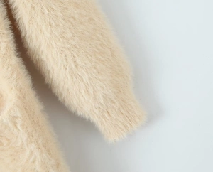 Close-up of fluffy beige long-pile faux fur texture on long hooded cardigan sleeve