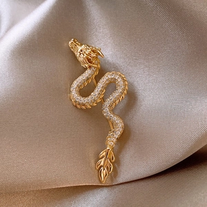 Detail of gold-plated dragon brooch with sparkling white zircons on champagne silk