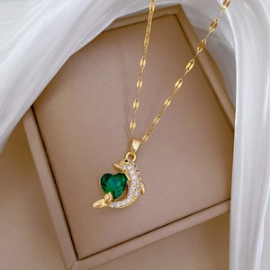 Detailed shot of golden dolphin pendant with green heart crystal on soft tulle