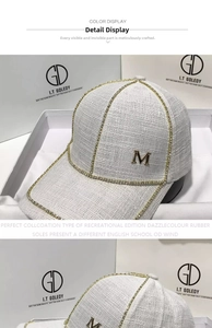 Close-up of white tweed baseball cap with gold rhinestone trim and metal letter M