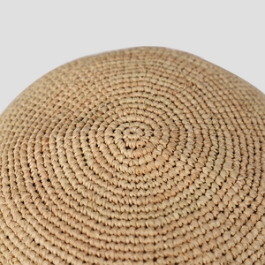 Close-up of tightly woven raffia fiber texture on a natural summer sun hat brim